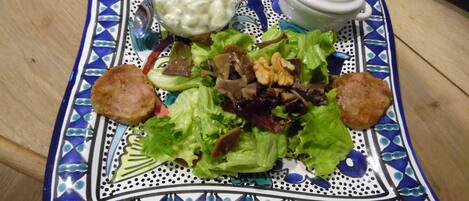 A plate of salad with croutons and a jar of dressing on a decorative blue and white plate.
