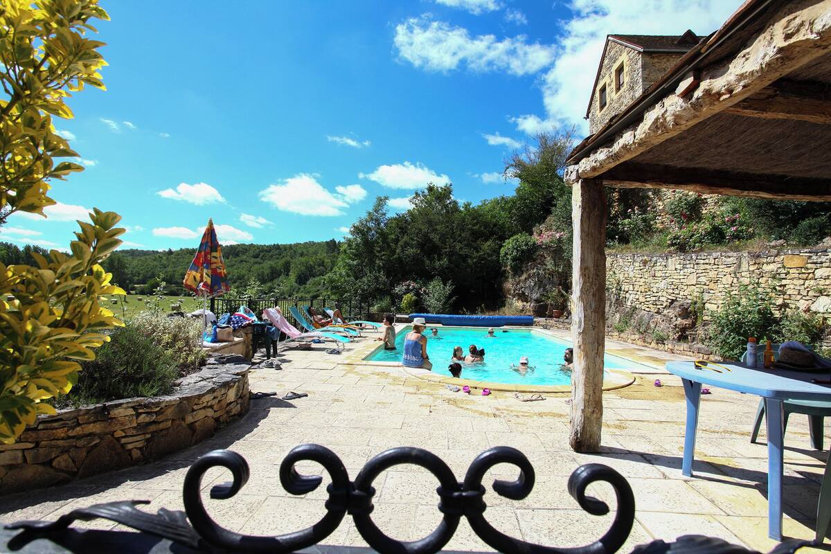 A swimming pool area with lounge chairs and a stone wall.