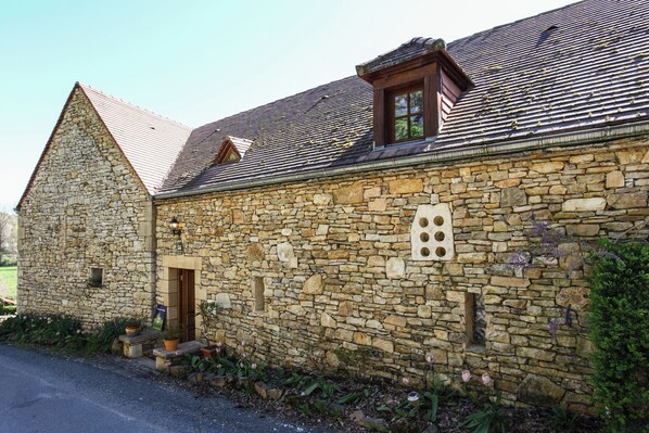Un bâtiment en pierre avec un toit en pente, une petite fenêtre et une porte.
