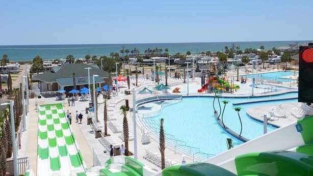 A resort with multiple swimming pools, a water slide, and a beach view.