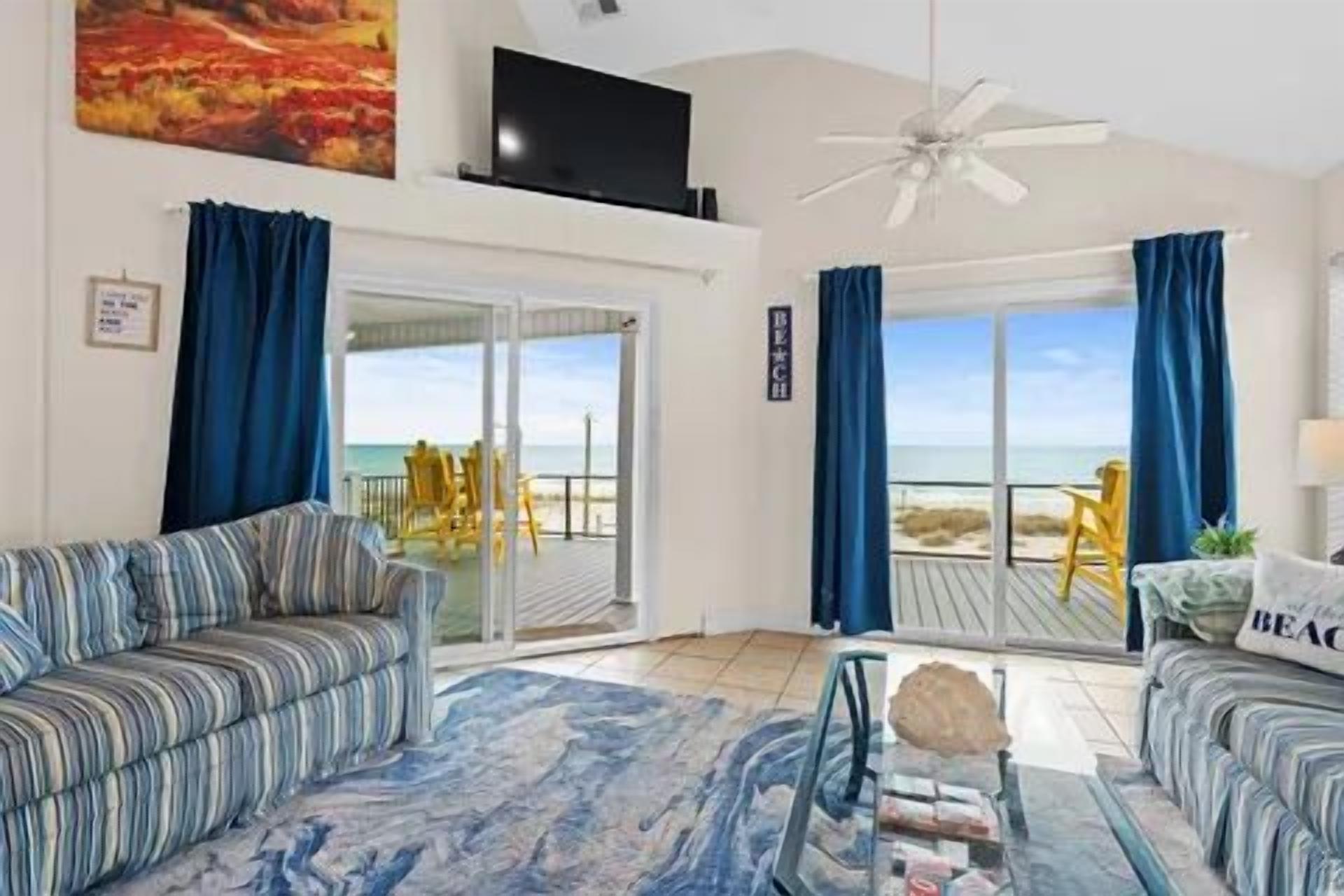 A living room with a sofa, a coffee table, and a view of the beach.