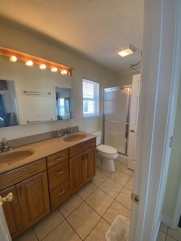 A bathroom with a double sink vanity, a toilet, and a shower.