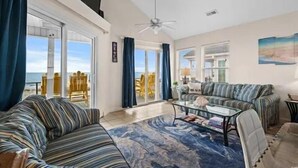 A spacious living room with a large window, a ceiling fan, and a view of the ocean.