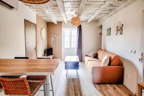 Ein gemütliches Wohnzimmer mit einem Holzesstisch, einer Couch und einem Fernseher.