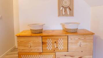 A wooden dresser with multiple drawers and two framed dreamcatchers on the wall above.