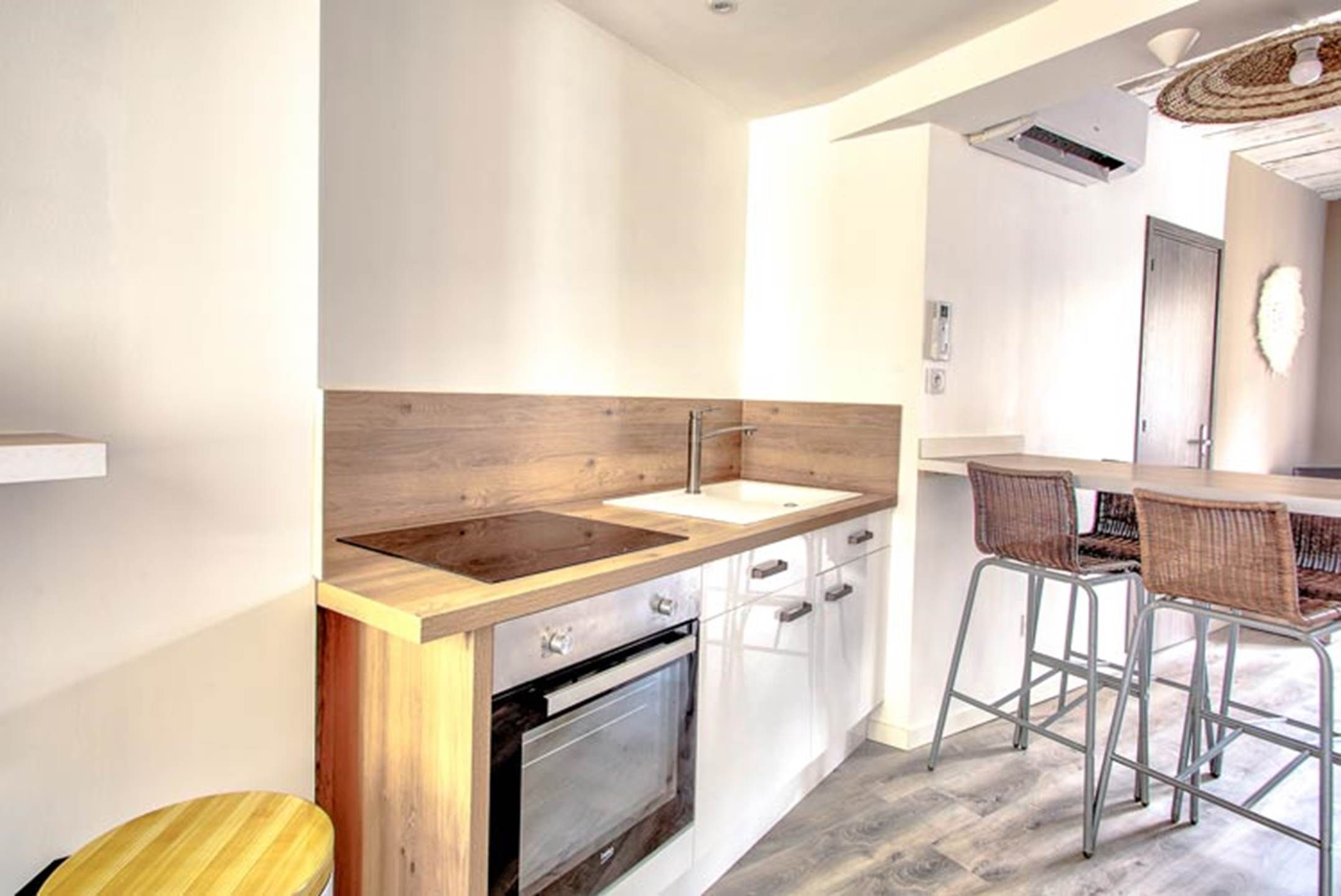 Une cuisine moderne dotée d’un plan de travail en bois, d’un four encastré et d’un coin bar avec des tabourets.