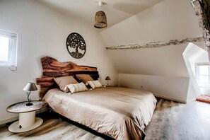 Ein Schlafzimmer mit einem hölzernen Kopfteil, einem Bett mit vielen Kissen, einer Nachttischlampe und einem Wanddekor.