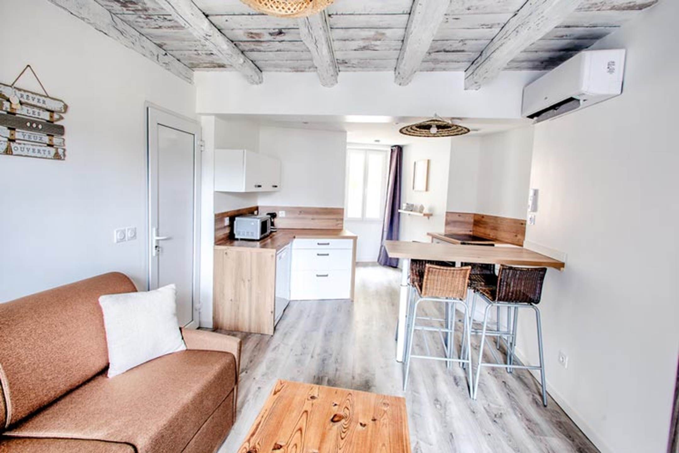 A compact living space with a kitchenette, a sofa, a coffee table, and a dining area.