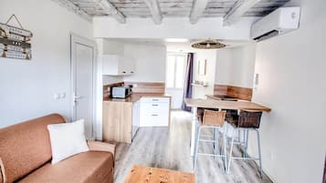 A compact living space with a kitchenette, a sofa, a coffee table, and a dining area.