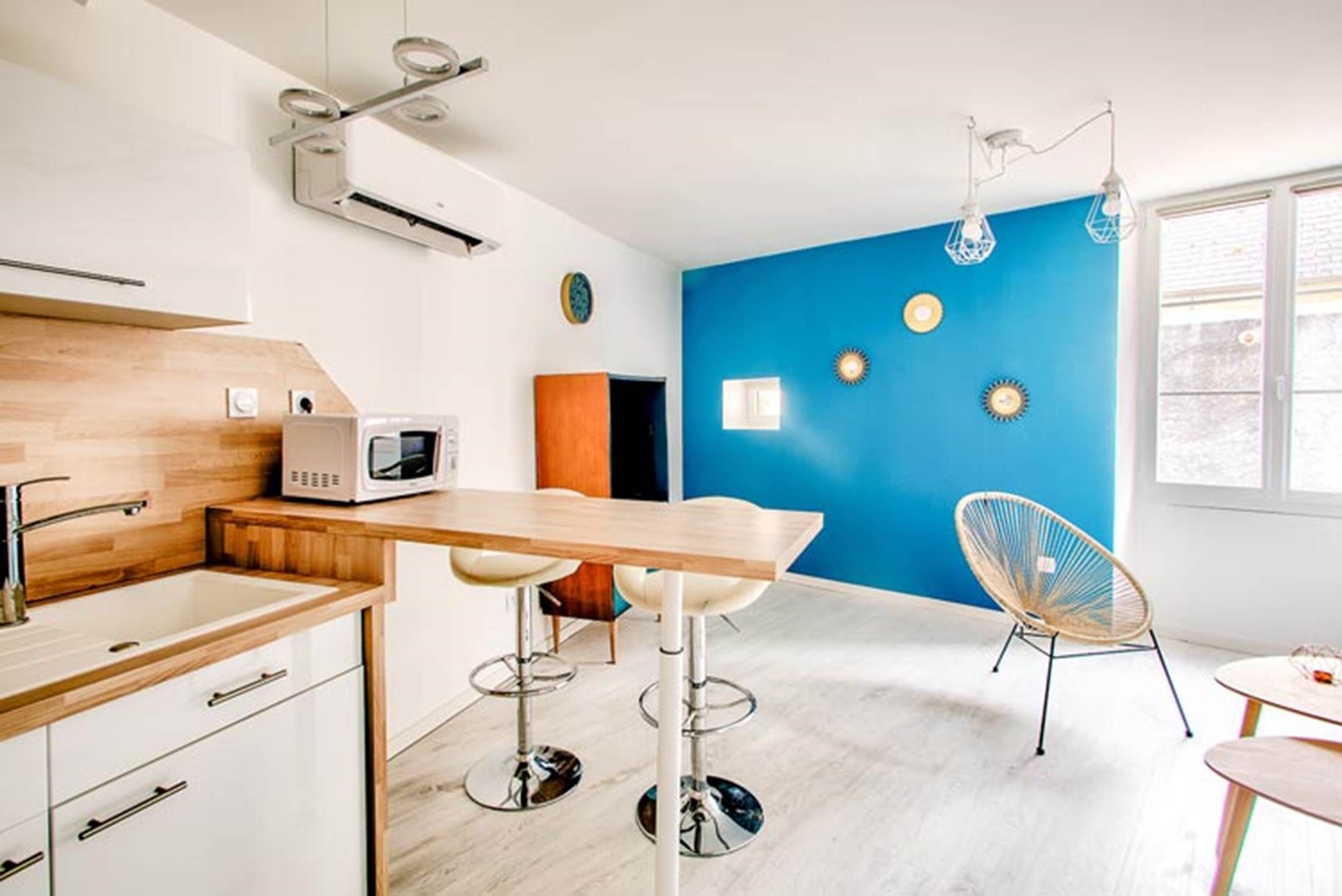 Une cuisine moderne avec un plan de travail en bois, un four à micro-ondes et un tabouret de bar.