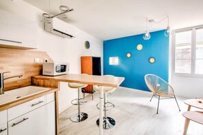 A modern kitchen with a wooden countertop, a microwave, and a bar stool.