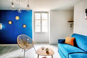 A living room with a blue sofa, a wicker chair, and a small round table.