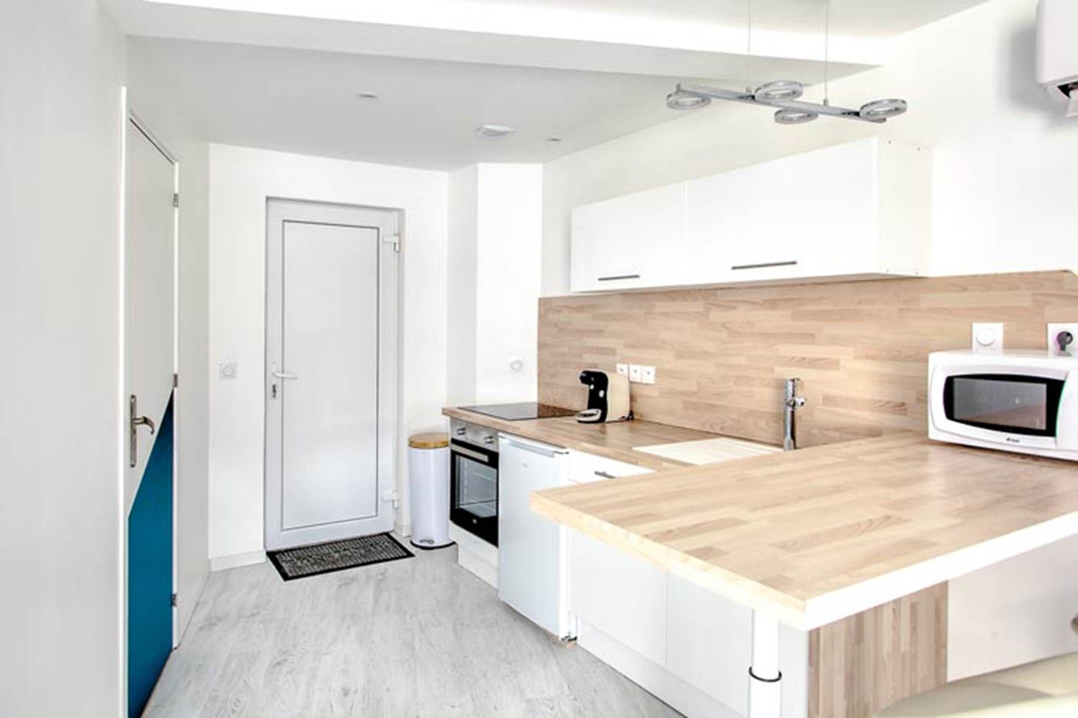 Een moderne keuken met een houten aanrecht, een inbouwoven, een magnetron en een koffieapparaat.