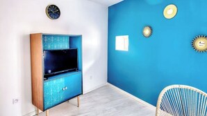 Une pièce avec un mur d’accent bleu, un meuble de rangement moderne pour les appareils électroniques et des appliques murales décoratives.