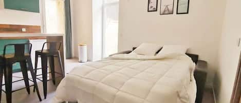 A bedroom with a bed, a desk, and a chair.