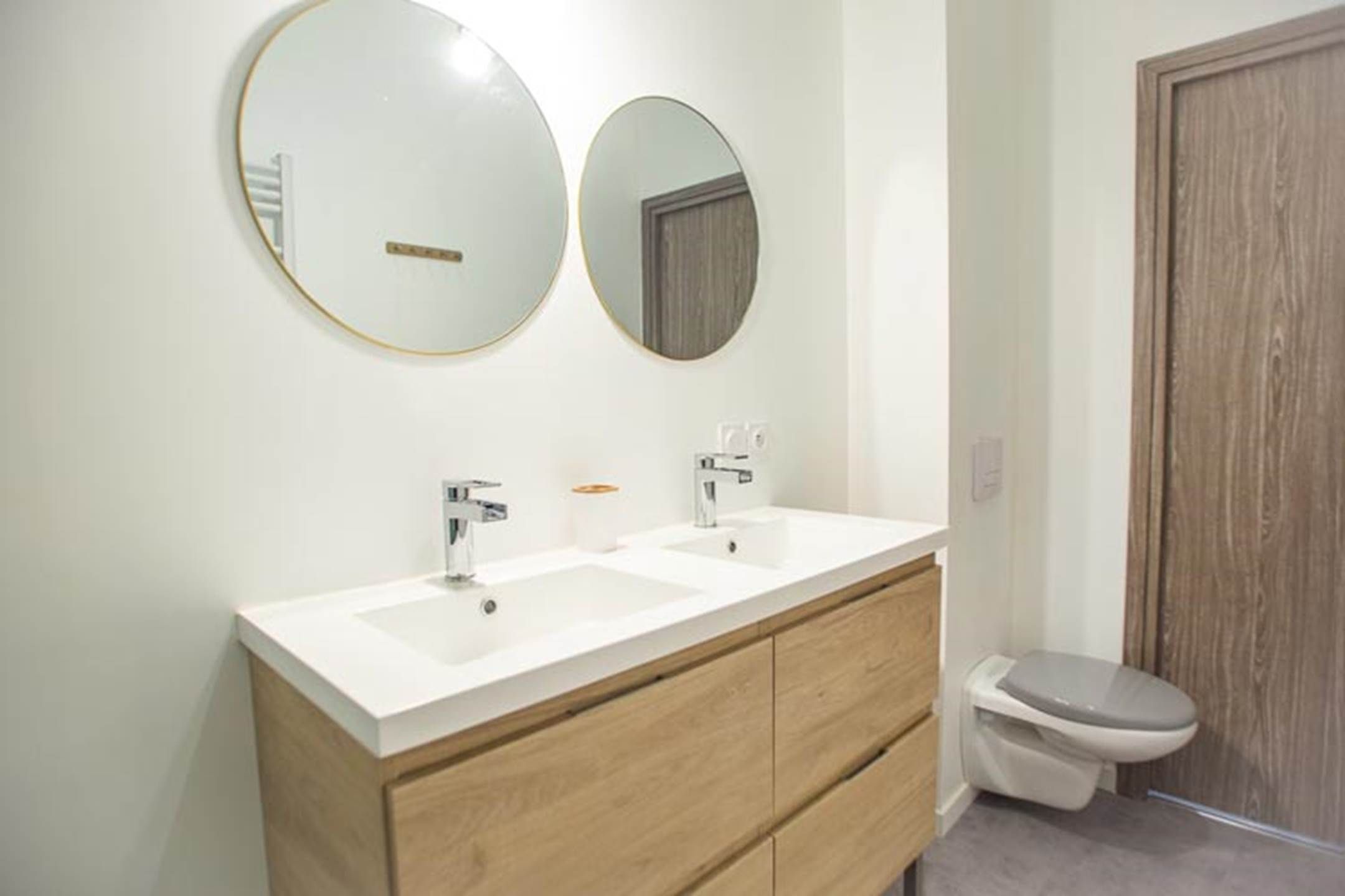 Une salle de bain avec deux lavabos, un miroir et des toilettes.