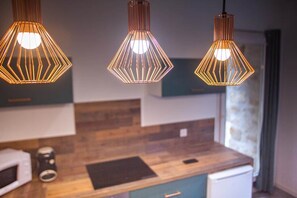 A modern kitchen with wooden countertops, a microwave, and three pendant lights with a geometric design.