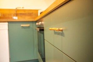 A kitchen with teal cabinets and a wooden countertop. - Rare T2 with terrace and spa at the foot of the castle (Montignac)