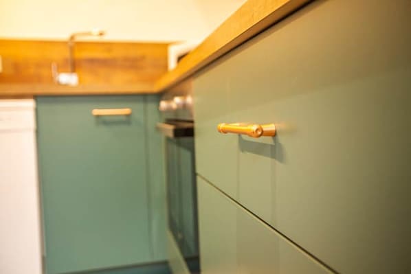 A kitchen with teal cabinets and a wooden countertop.