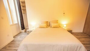 A bedroom with a large bed, two bedside tables with lamps, a closet, and a window.