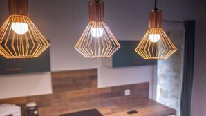 A modern kitchen with wooden countertops, a microwave, and three geometric pendant lights.