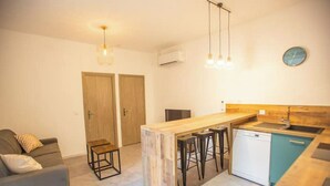 A compact kitchen with a wooden island, bar stools, and a small dishwasher.