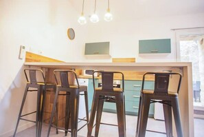 A kitchen with a central island, bar stools, and pendant lighting.