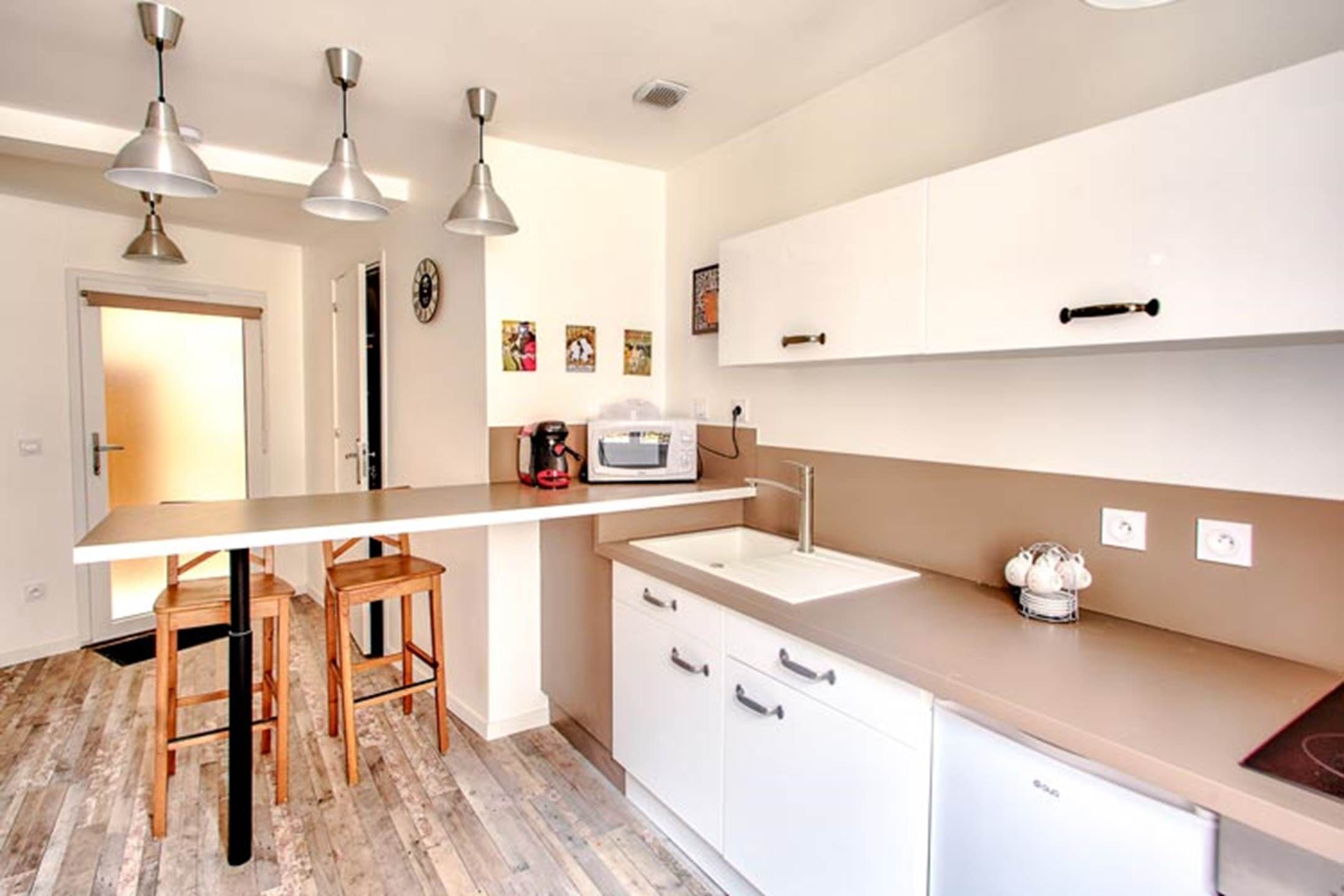 A modern kitchen with a central island, pendant lights, and a microwave.