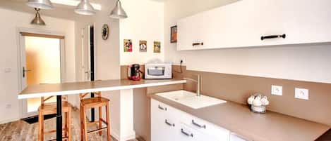 A modern kitchen with a central island, pendant lights, and a microwave.