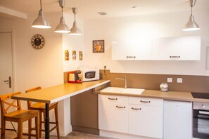Eine moderne Küche mit weißen Schränken, einem Holztisch und Pendelleuchten.