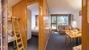 A cozy room with a wooden ladder, a sofa, a table with cups, and a window with a view of trees. - 50m from resort center, 6th floor, balcony, 40m², Les Arcs (Les Arcs)