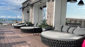 Une terrasse sur le toit, avec un mur en pierre, des sièges extérieurs et une vue sur le panorama de la ville.