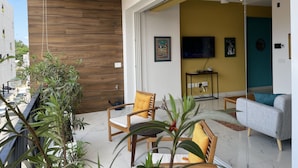 Un salon moderne avec un canapé, des fauteuils et un téléviseur.