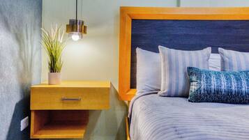 A bedroom with a bed, a nightstand, a hanging light, and a potted plant.