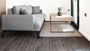 Ein modernes Wohnzimmer mit einem grauen Sofa, einem kleinen Couchtisch und einem Bild an der Wand.