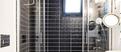 A modern bathroom with a glass-enclosed shower, a white toilet, and a sink with a round mirror.