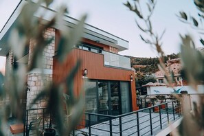 A modern building with a stone facade, large windows, and a metal railing. - Casa Mimosa Hotel (Karaburun)