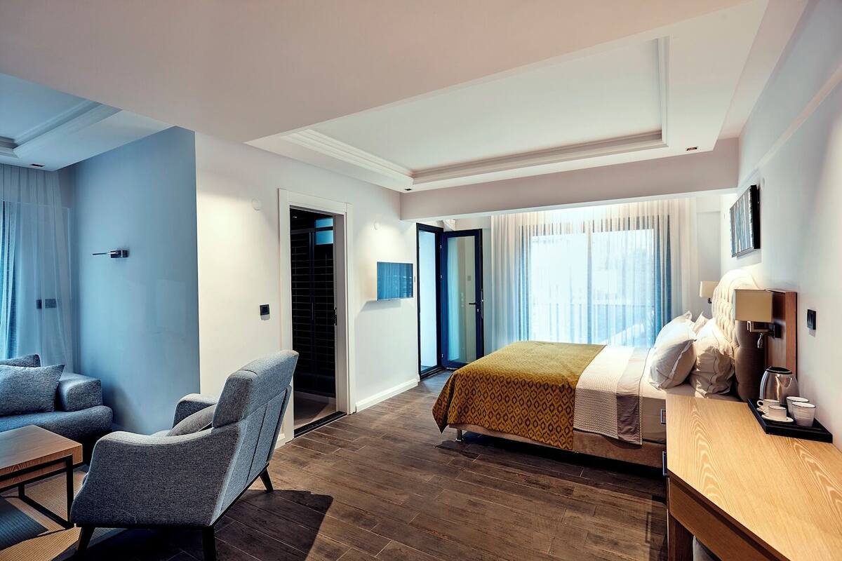 A modern hotel room with a bed, seating area, and a desk.