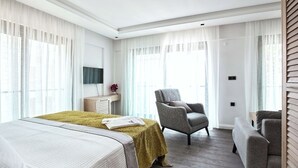 Ein Hotelzimmer mit einem Bett, zwei Sesseln, einem Schreibtisch und einem Fernseher.