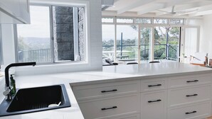 Cozinha moderna com uma ilha grande, armários brancos e vista para o exterior.