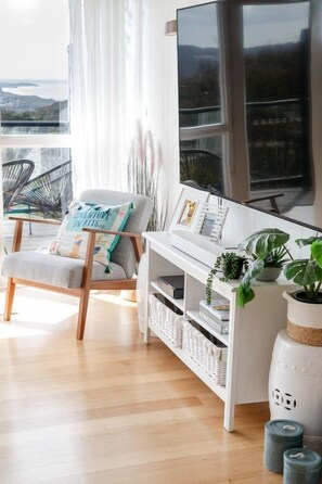 Ein modernes Wohnzimmer mit Blick, ein weißer Konsolentisch, ein Sessel und ein großes Fenster.