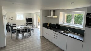 A modern kitchen with white cabinets, a black countertop, and a window above the sink. - APARTMENT "ILE BONO" WITH GARDEN, 800 ml BEACH (Perros-Guirec)