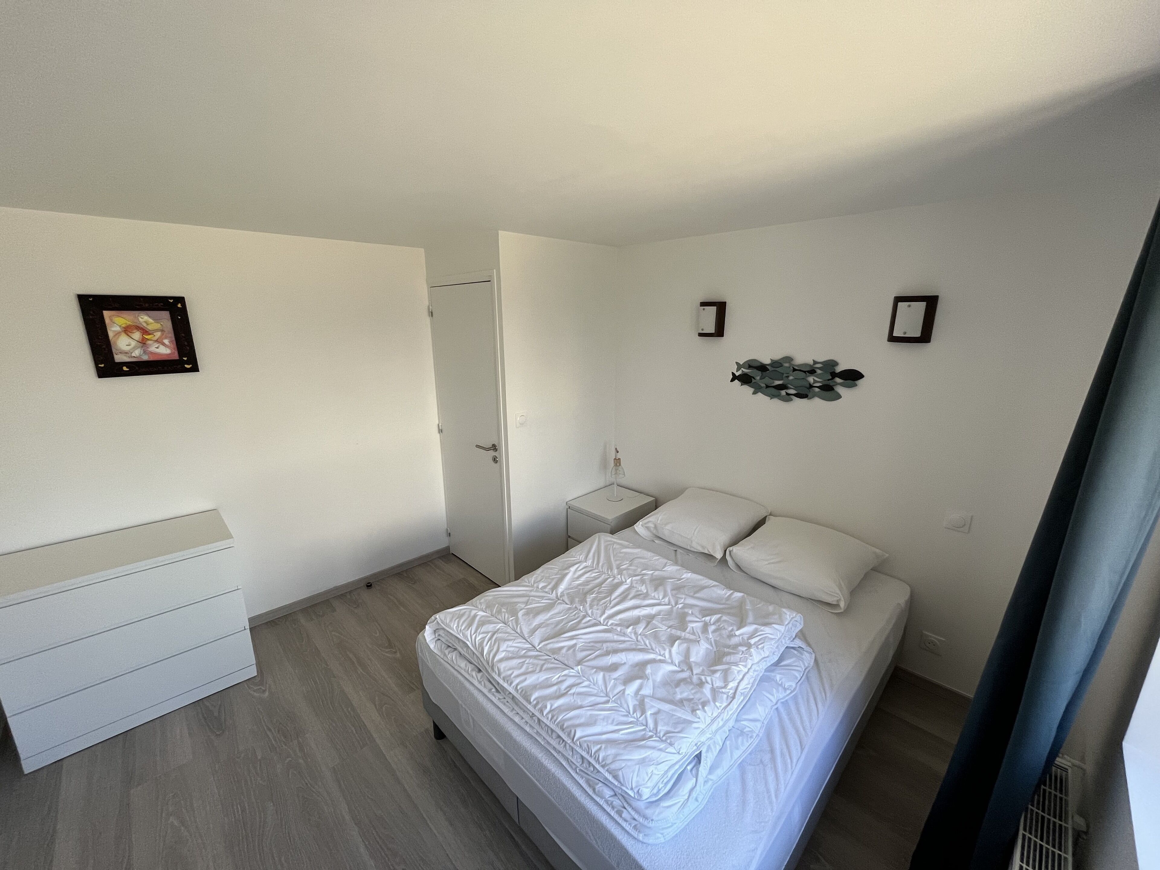Une chambre à coucher avec un lit, une table de chevet, une commode et une porte.