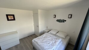 A bedroom with a bed, a bedside table, a dresser, and a door. - APARTMENT "ILE BONO" WITH GARDEN, 800 ml BEACH (Perros-Guirec)