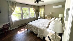 A bedroom with a bed, a nightstand, a lamp, a ceiling fan, a window with curtains, and a mirror. - Lakefront • Hot Tub • Private Dock • Kayaks • Canoe • Fire Pit • Dog Friendly (Coolbaugh Township)