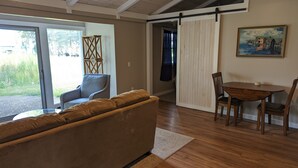 Een woonkamer met een bank, een eettafel met stoelen, een houten vloer en een schuifdeur die uitkomt op een balkon.
