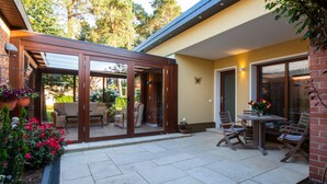 A patio with outdoor seating, a table, and a garden area with flowers and plants. - Exclusive vacation home in the Dichterviertel (Brück)