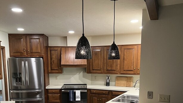 A modern kitchen with wooden cabinets, stainless steel appliances, and pendant lighting. - Country Club Casa the Golfer's Getaway!!! (Duncan)