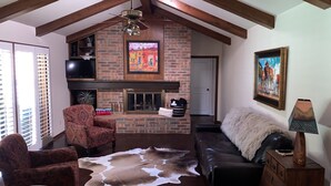 A living room with a fireplace, a leather sofa, a patterned armchair, and a cowhide rug. - Country Club Casa the Golfer's Getaway!!! (Duncan)