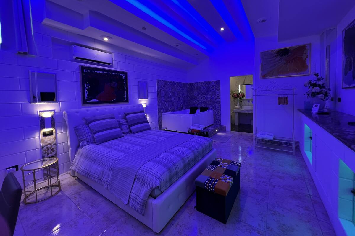 Un dormitorio moderno con una cama grande, un tocador y un baño visible a través de una puerta abierta.